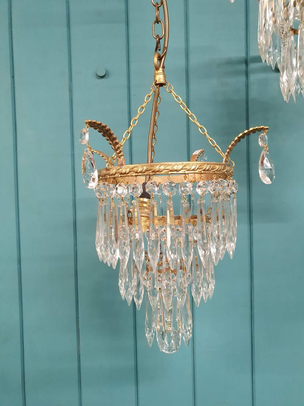 A pair of early 20th-century brass ceiling pendant chandeliers featuring tiered cut crystal spikes and hanging drops. View VI