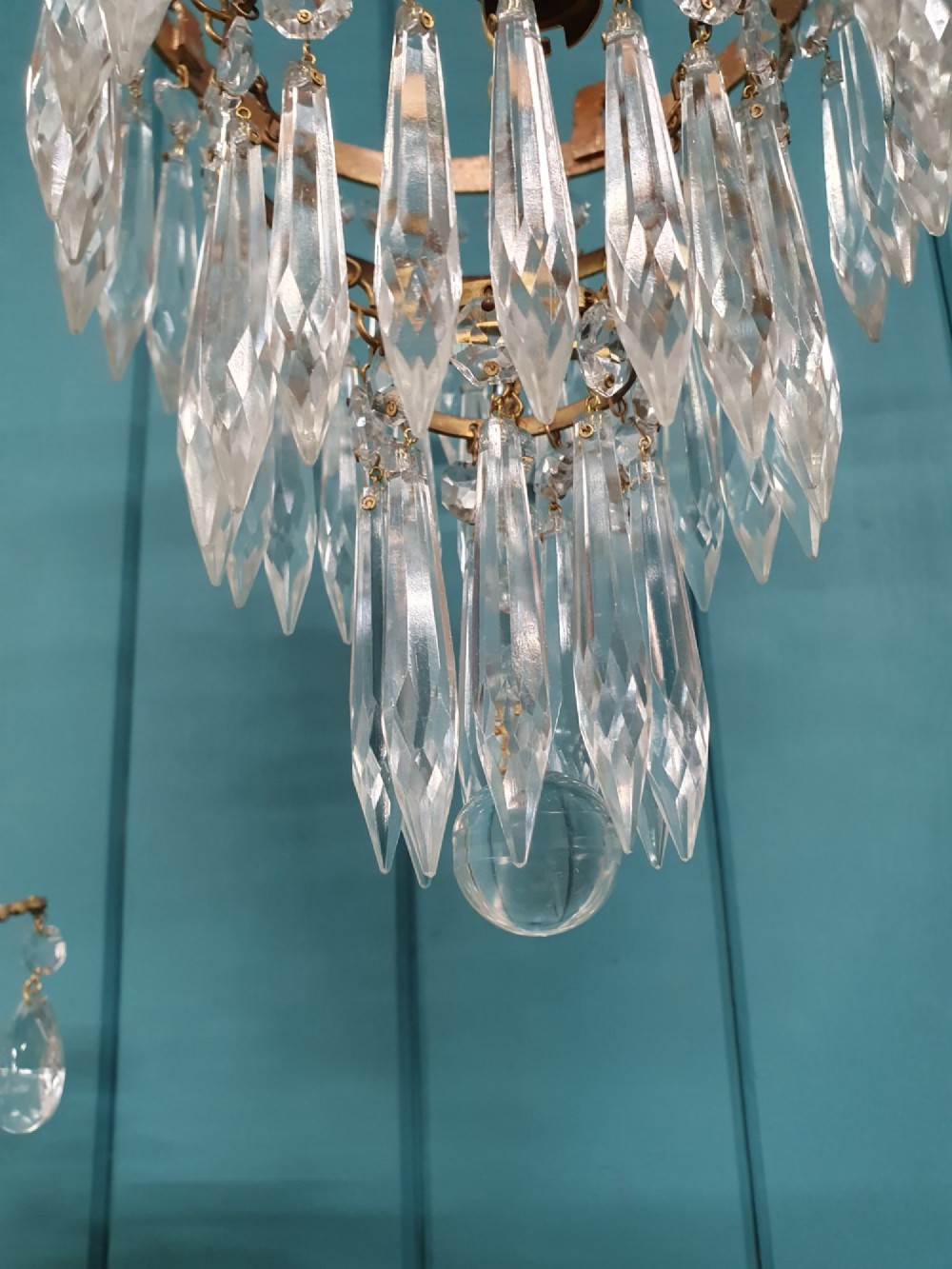 A pair of early 20th-century brass ceiling pendant chandeliers featuring tiered cut crystal spikes and hanging drops. View VII