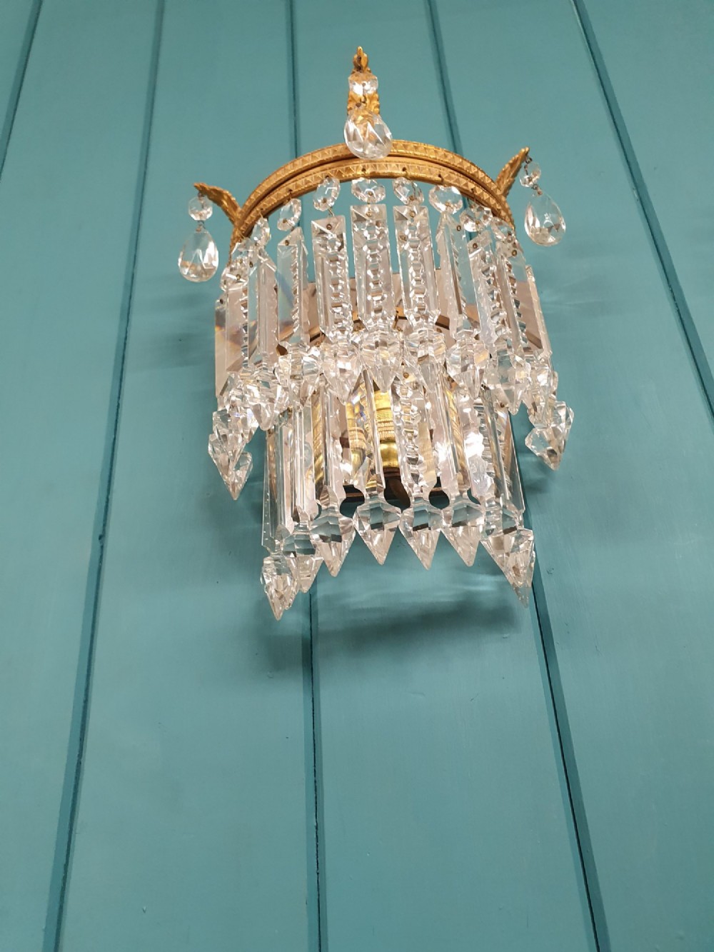A pair of antique gilt brass wall lights with cascading tiers of cut glass crystal prisms. View V