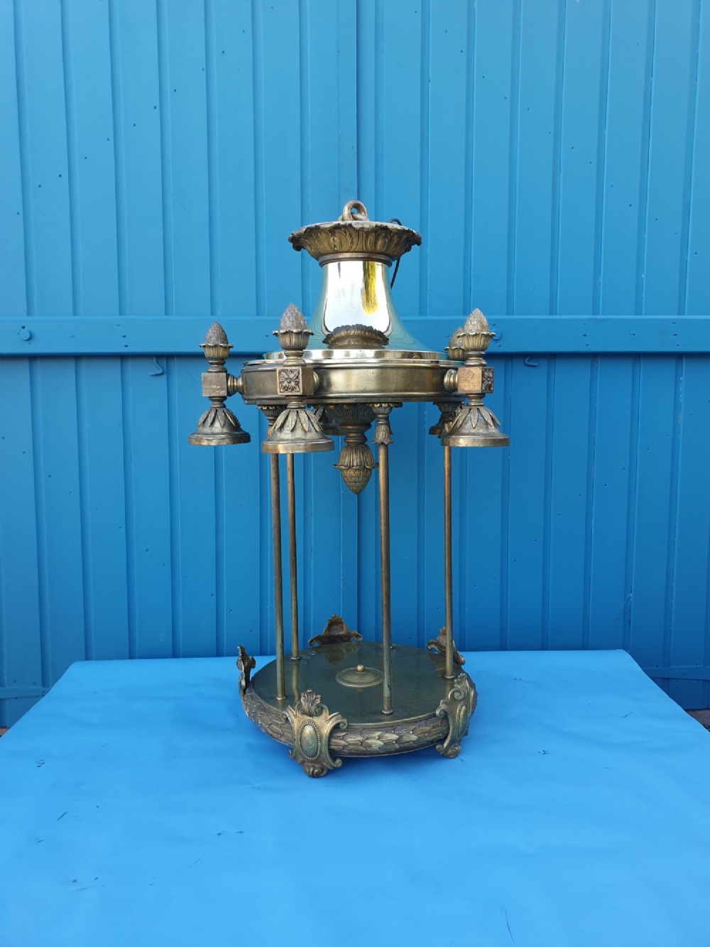 A pair of large early 20th-century brass hall lanterns featuring open columnar frames, acanthus leaf embellishments, decorative lower bands, and top hanging loops. View X
