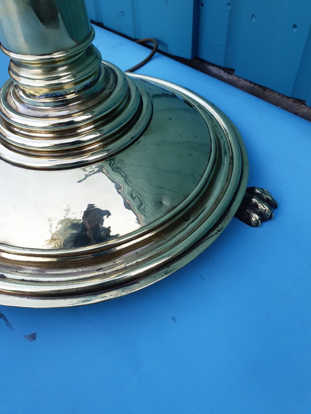 A tall, polished brass floor-standing lantern lamp featuring a hexagonal glass enclosure mounted on a slender turned stem and a circular stepped base with paw feet. View II