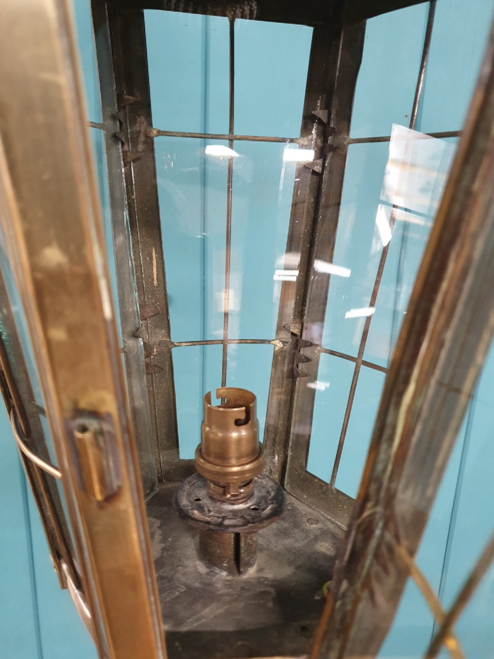 A tall, polished brass floor-standing lantern lamp featuring a hexagonal glass enclosure mounted on a slender turned stem and a circular stepped base with paw feet. View IV