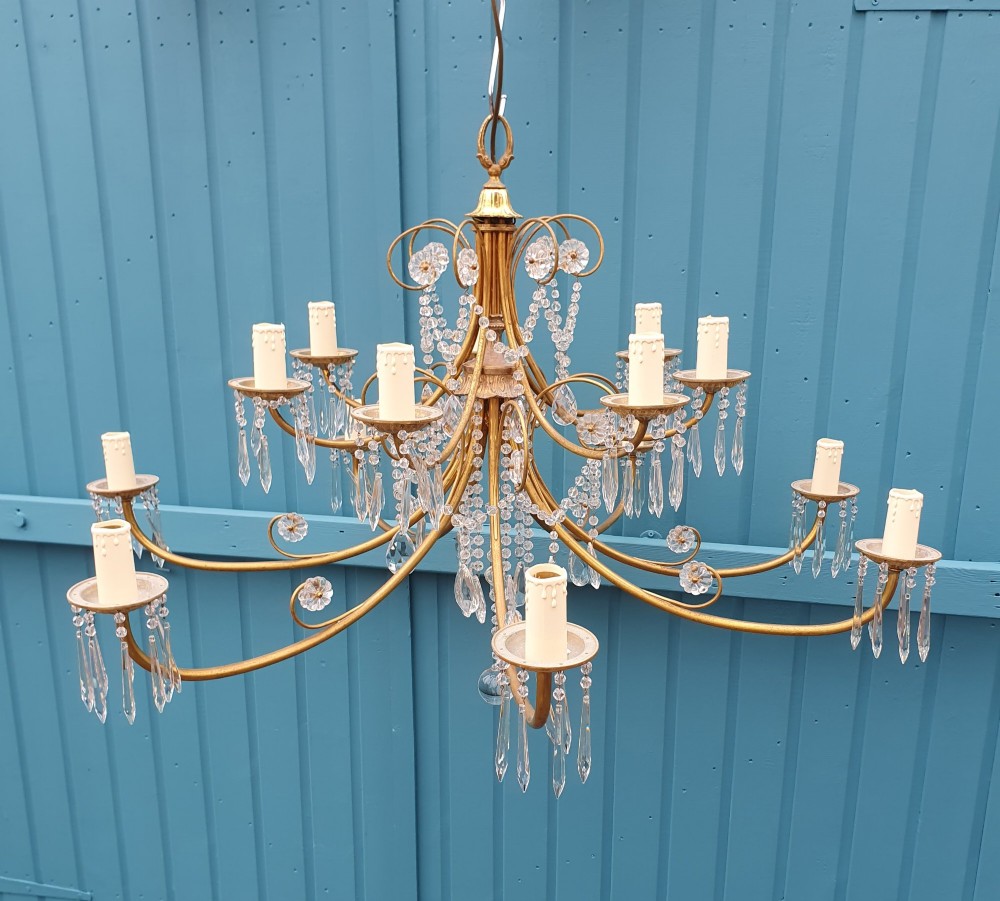 A pair of brass two-tier fourteen-arm chandeliers adorned with cut glass crystal droplets and faux candle light sockets. View IV