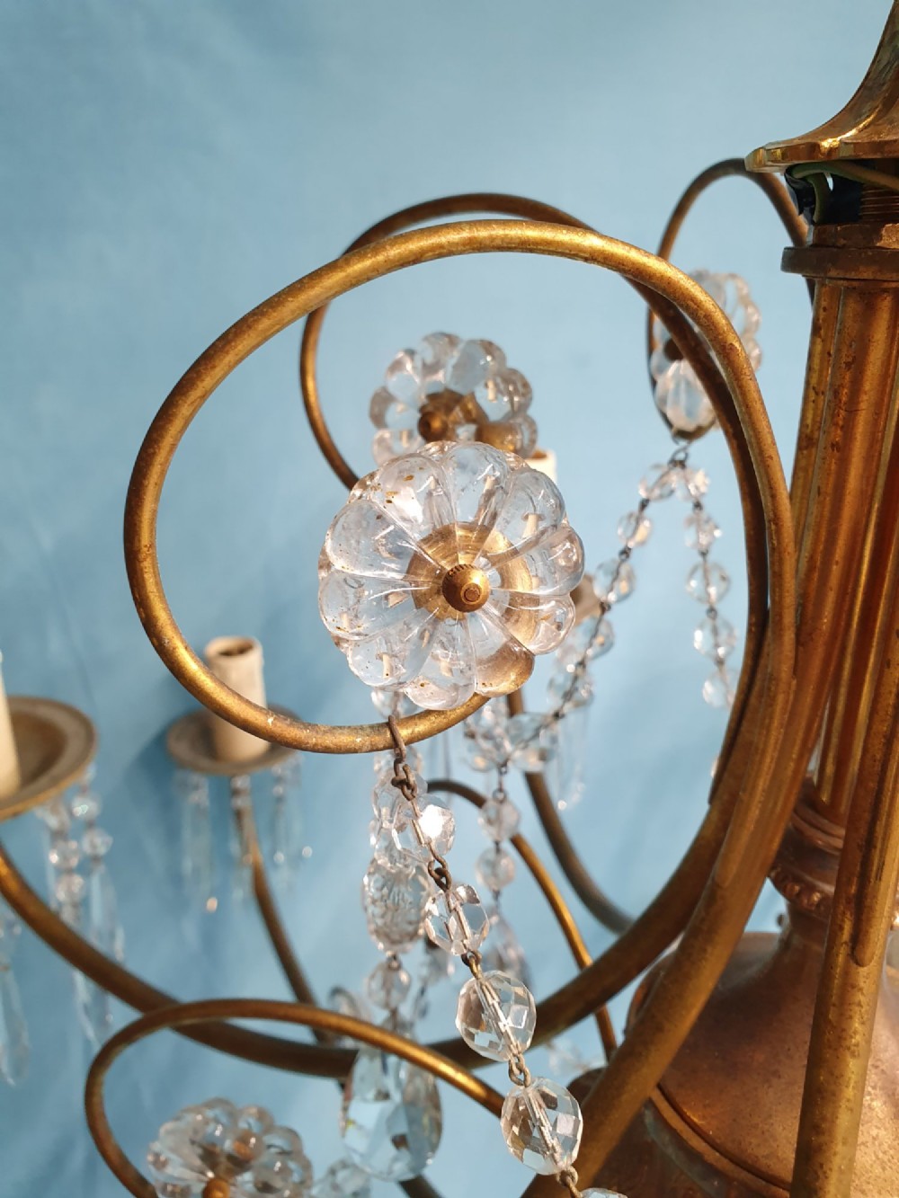 A pair of brass two-tier fourteen-arm chandeliers adorned with cut glass crystal droplets and faux candle light sockets. View X