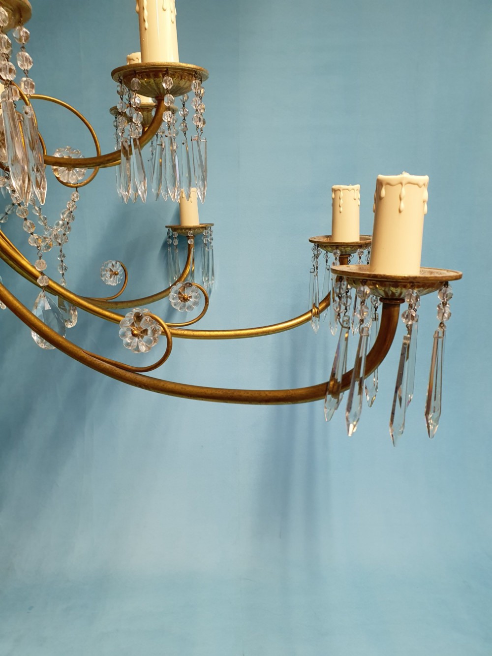 A pair of brass two-tier fourteen-arm chandeliers adorned with cut glass crystal droplets and faux candle light sockets. View XIII