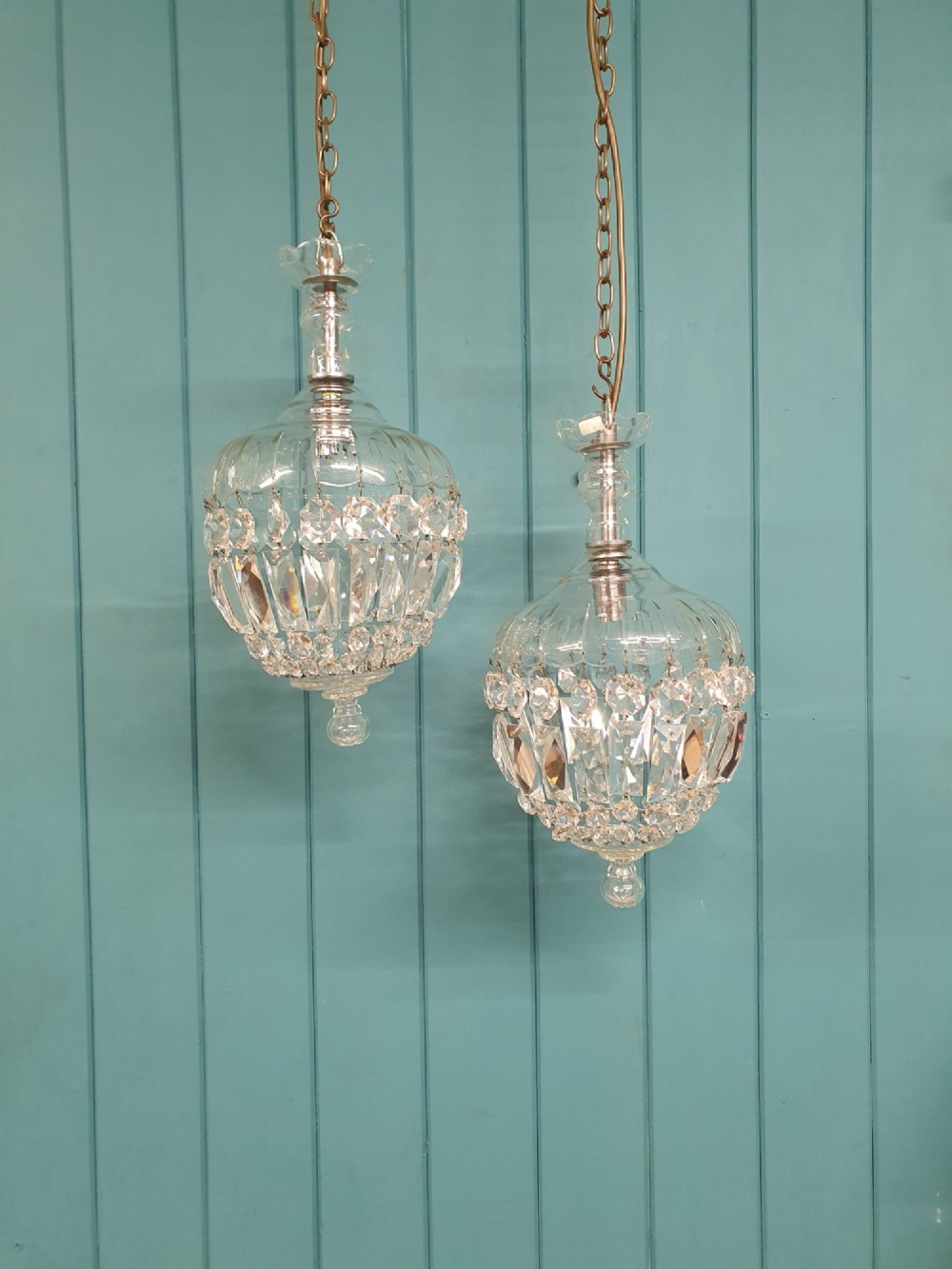 A pair of early 20th-century crystal bag pendant lights featuring dome glass tops and cascading cut glass drops hanging from brass chains.