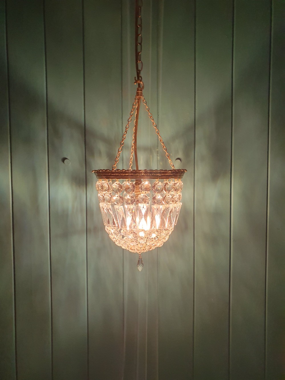 An early twentieth-century gilt brass basket chandelier suspended by chains with tiered cut glass prisms. View III