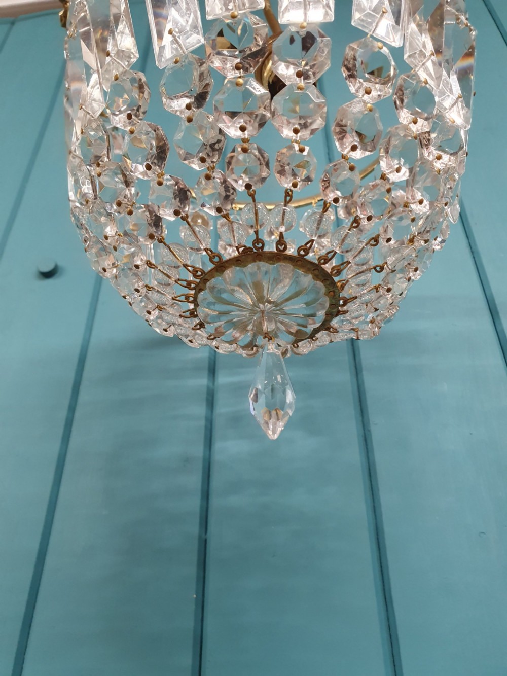 An early twentieth-century gilt brass basket chandelier suspended by chains with tiered cut glass prisms. View IV