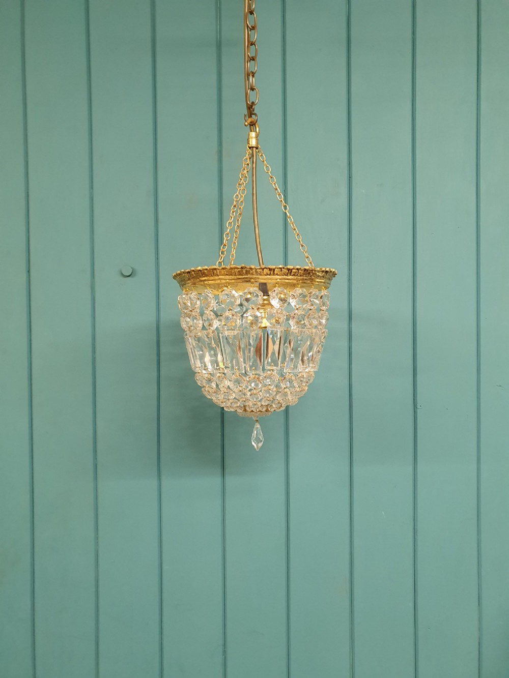 An early twentieth-century gilt brass basket chandelier suspended by chains with tiered cut glass prisms.