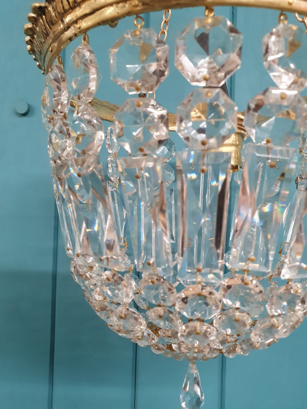 An early twentieth-century gilt brass basket chandelier suspended by chains with tiered cut glass prisms. View V