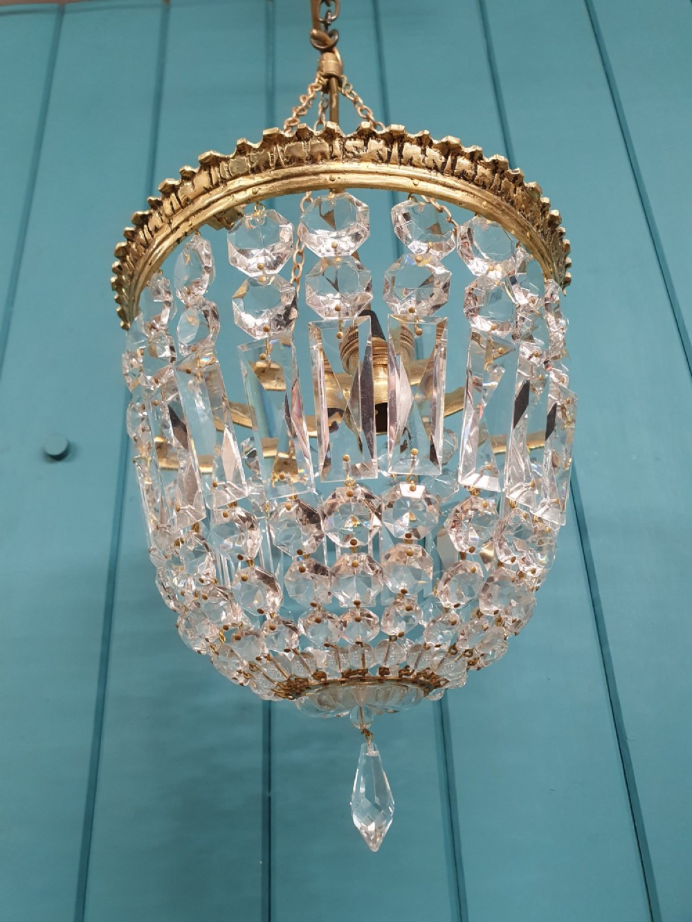 An early twentieth-century gilt brass basket chandelier suspended by chains with tiered cut glass prisms. View VI