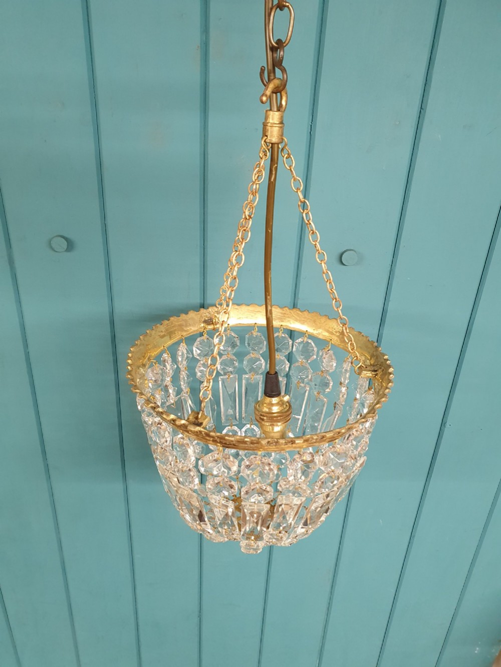 An early twentieth-century gilt brass basket chandelier suspended by chains with tiered cut glass prisms. View VII
