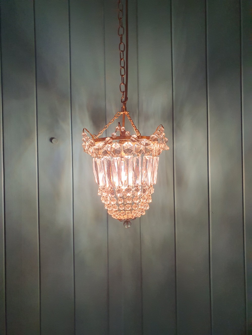 An early 20th-century gilt brass and crystal bag chandelier suspended by a link chain, featuring cascading faceted prisms and glass bead strands. View II