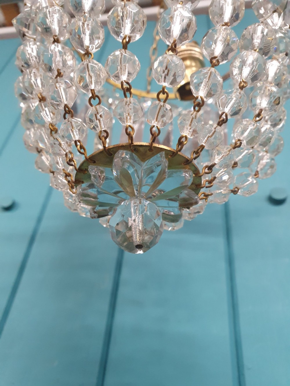 An early 20th-century gilt brass and crystal bag chandelier suspended by a link chain, featuring cascading faceted prisms and glass bead strands. View IV
