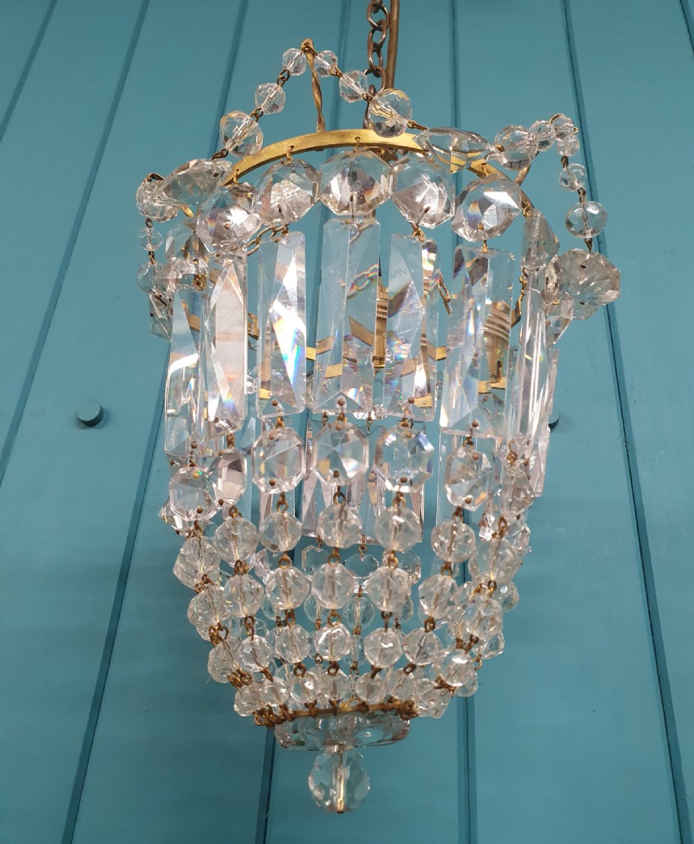 An early 20th-century gilt brass and crystal bag chandelier suspended by a link chain, featuring cascading faceted prisms and glass bead strands. View VI