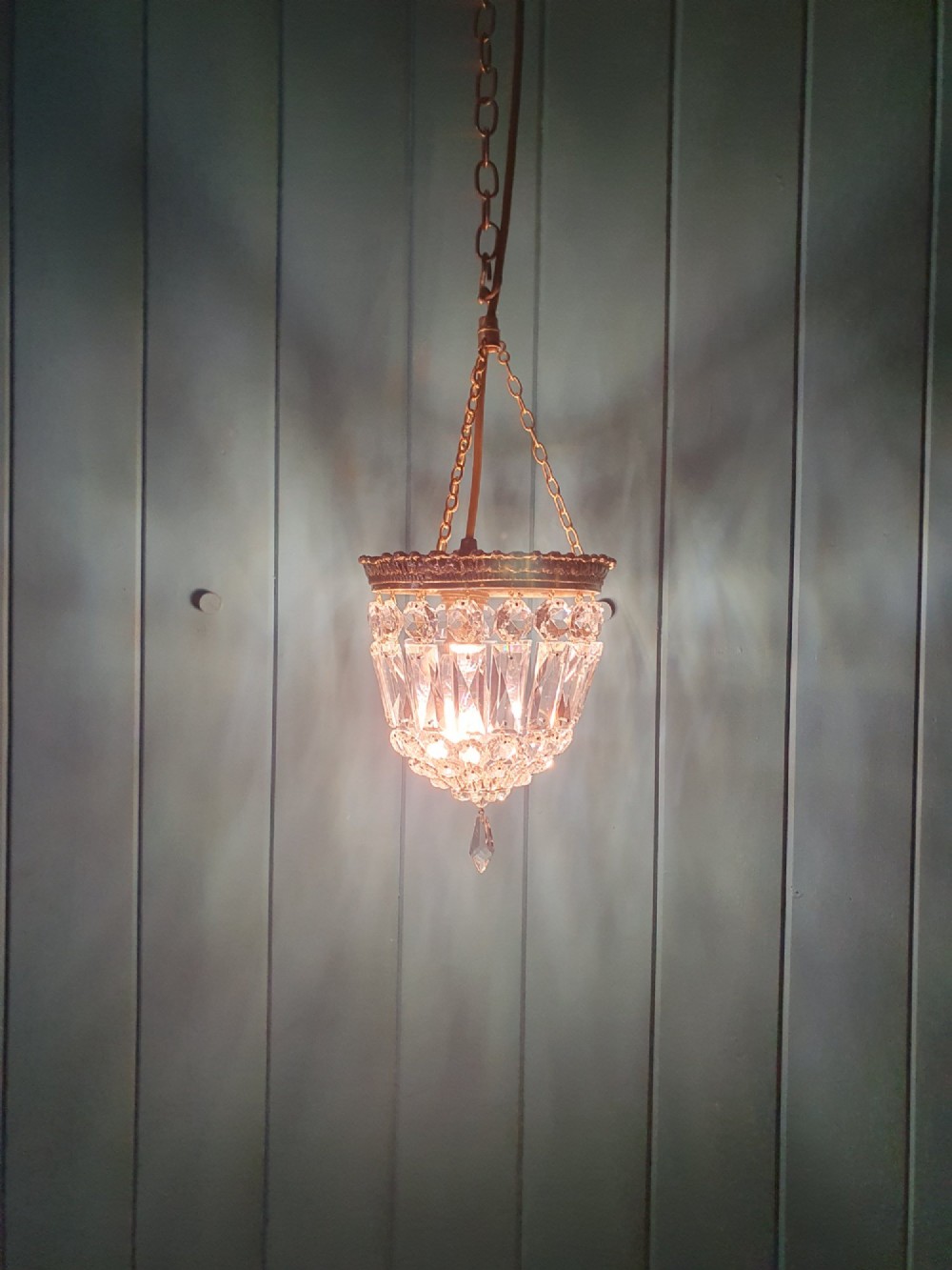 An early twentieth-century gilt brass crystal basket chandelier featuring faceted glass prisms and a suspended chain hanger. View II