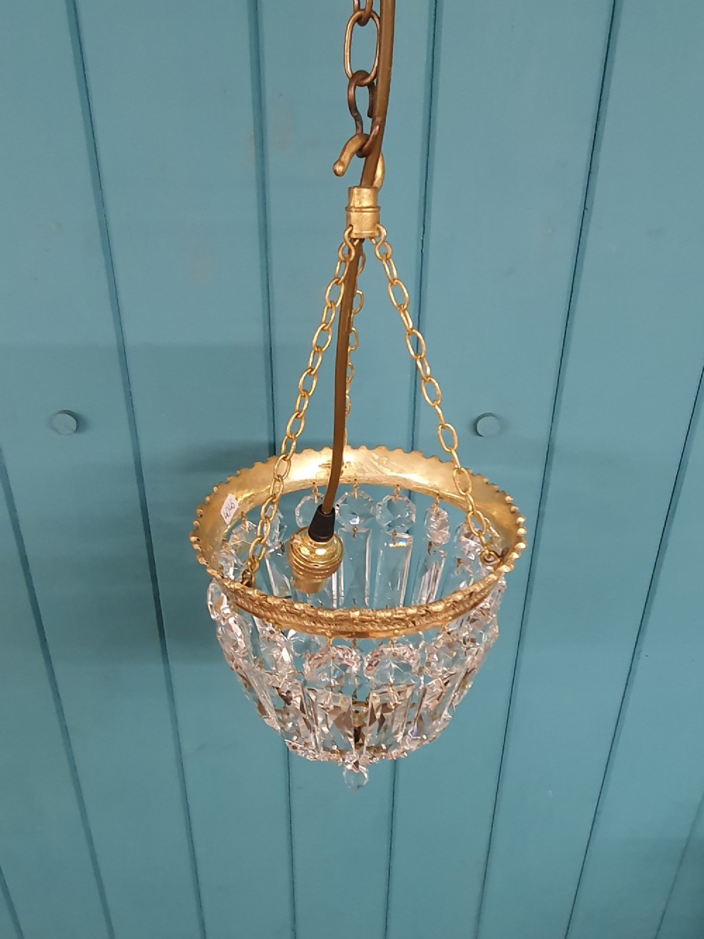 An early twentieth-century gilt brass crystal basket chandelier featuring faceted glass prisms and a suspended chain hanger. View VI