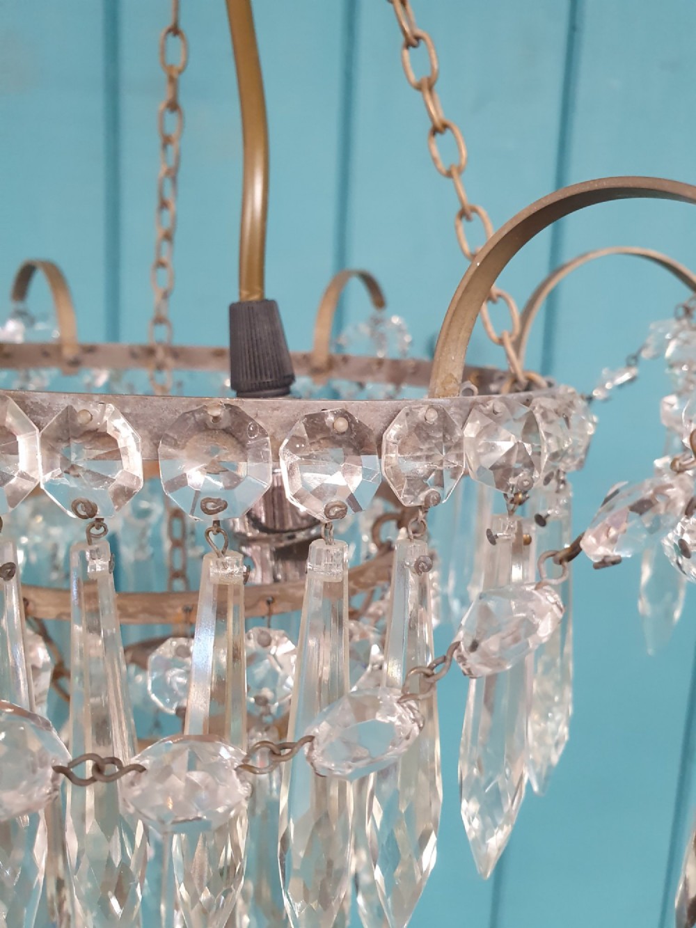 An early 20th century brass light fitting featuring cascading tiers of cut glass crystal teardrops suspended from brass chains. View V