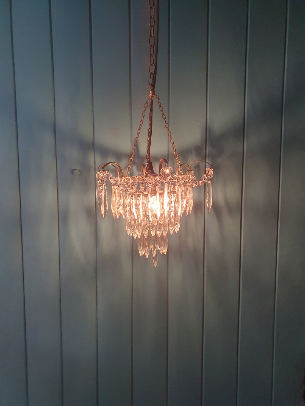An early 20th century brass light fitting featuring cascading tiers of cut glass crystal teardrops suspended from brass chains. View VI