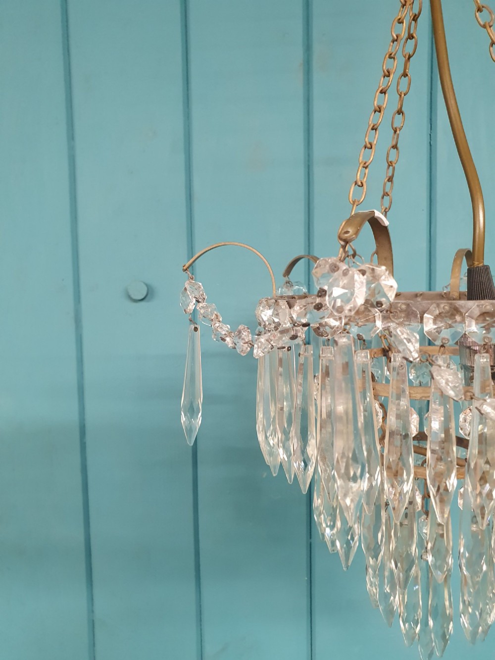 An early 20th century brass light fitting featuring cascading tiers of cut glass crystal teardrops suspended from brass chains. View VII