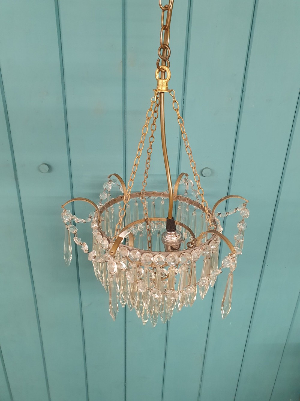 An early 20th century brass light fitting featuring cascading tiers of cut glass crystal teardrops suspended from brass chains. View VIII