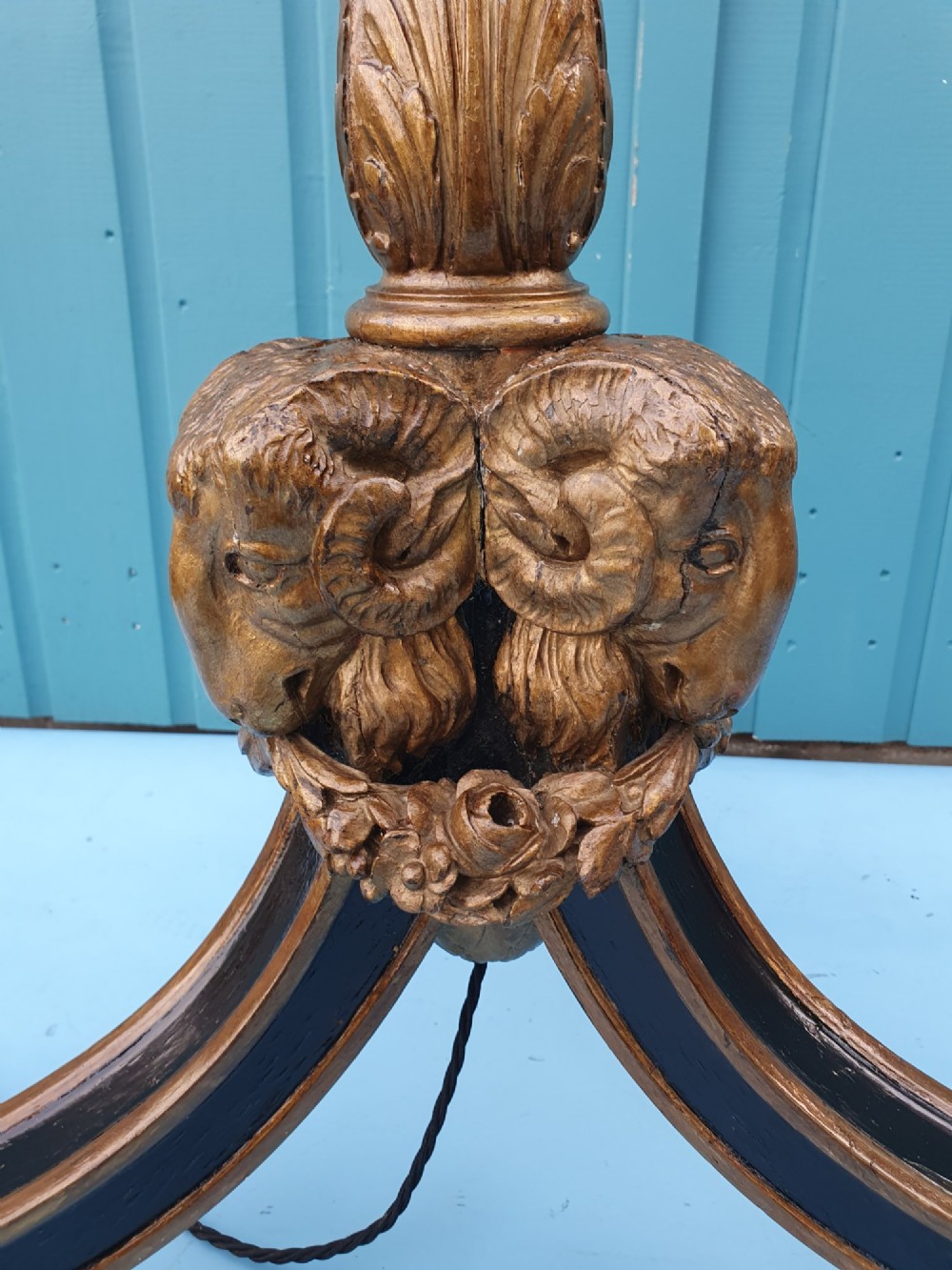 A tall antique carved giltwood standard lamp featuring a fluted column and triform base set against a blue panelled wall. View VI