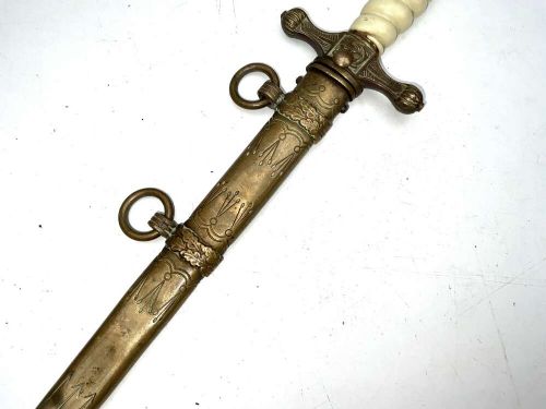 A German Kriegsmarine officer dress dagger featuring a cream wire-wrapped grip, spherical eagle pommel, crossguard, and an engraved brass scabbard with two suspension rings. View II