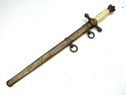 A German Kriegsmarine officer dress dagger featuring a cream wire-wrapped grip, spherical eagle pommel, crossguard, and an engraved brass scabbard with two suspension rings. View IV