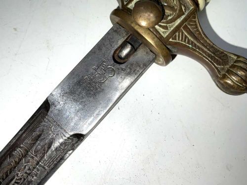 A German Kriegsmarine officer dress dagger featuring a cream wire-wrapped grip, spherical eagle pommel, crossguard, and an engraved brass scabbard with two suspension rings. View VIII