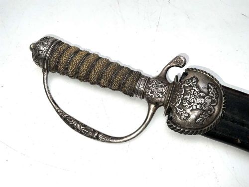 An early 18th-century short sword featuring a silvered hilt and ribbed grip, displayed alongside its black leather scabbard. View II