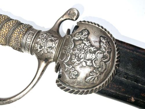 An early 18th-century short sword featuring a silvered hilt and ribbed grip, displayed alongside its black leather scabbard. View IV