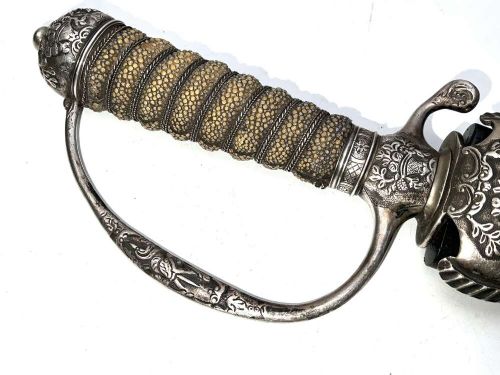 An early 18th-century short sword featuring a silvered hilt and ribbed grip, displayed alongside its black leather scabbard. View V