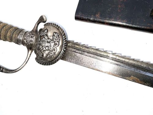 An early 18th-century short sword featuring a silvered hilt and ribbed grip, displayed alongside its black leather scabbard. View X