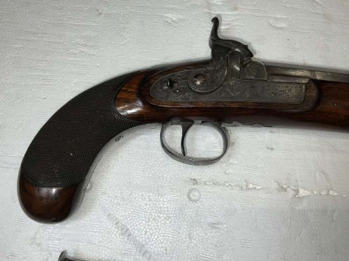 A pair of nineteenth-century percussion pistols featuring dark walnut stocks, octagonal steel barrels, engraved lockplates, and captive swivel ramrods. View II