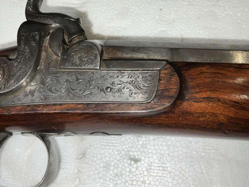 A pair of nineteenth-century percussion pistols featuring dark walnut stocks, octagonal steel barrels, engraved lockplates, and captive swivel ramrods. View III