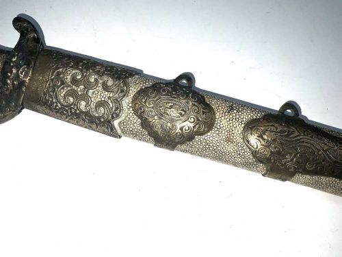 A Chinese double-edged Jian sword resting inside a detailed metal-mounted scabbard. View III