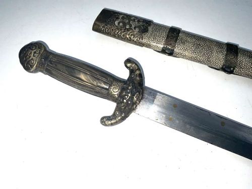 A Chinese double-edged Jian sword resting inside a detailed metal-mounted scabbard. View VII