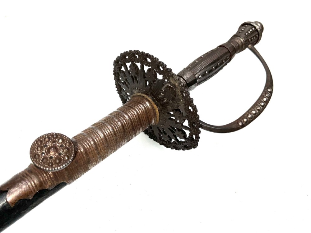 An 18th-century rapier sword featuring a dark leather scabbard and an intricately pierced round steel hilt guard. View II