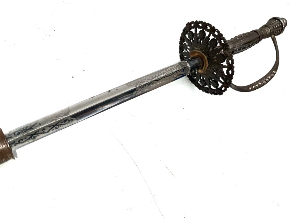 An 18th-century rapier sword featuring a dark leather scabbard and an intricately pierced round steel hilt guard. View III