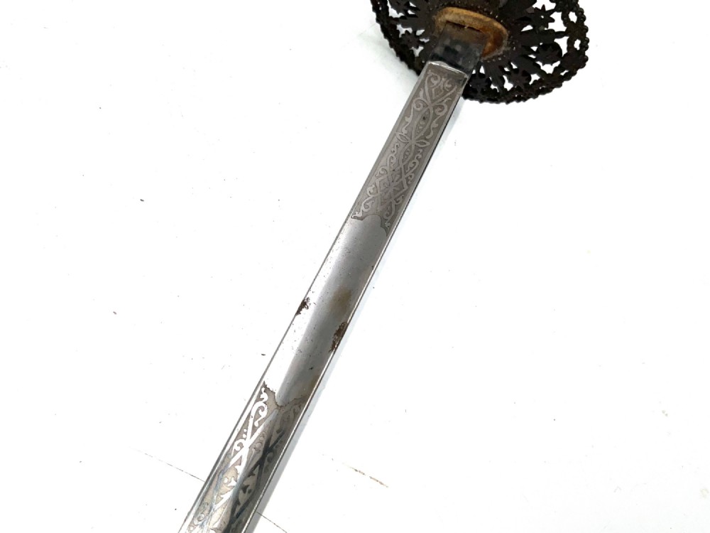 An 18th-century rapier sword featuring a dark leather scabbard and an intricately pierced round steel hilt guard. View V