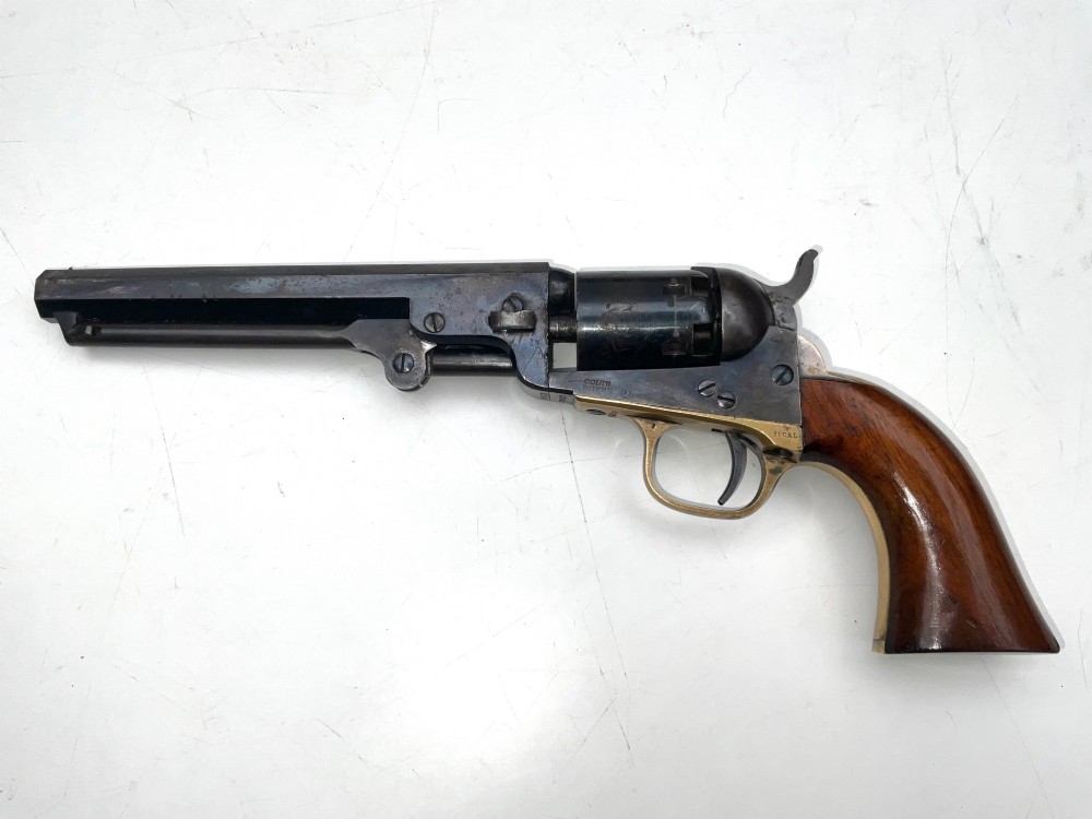 An open fitted wooden presentation case containing a .31 calibre percussion revolver, a brass powder flask, a bullet mould, and an instruction label attached to the inner lid. View II