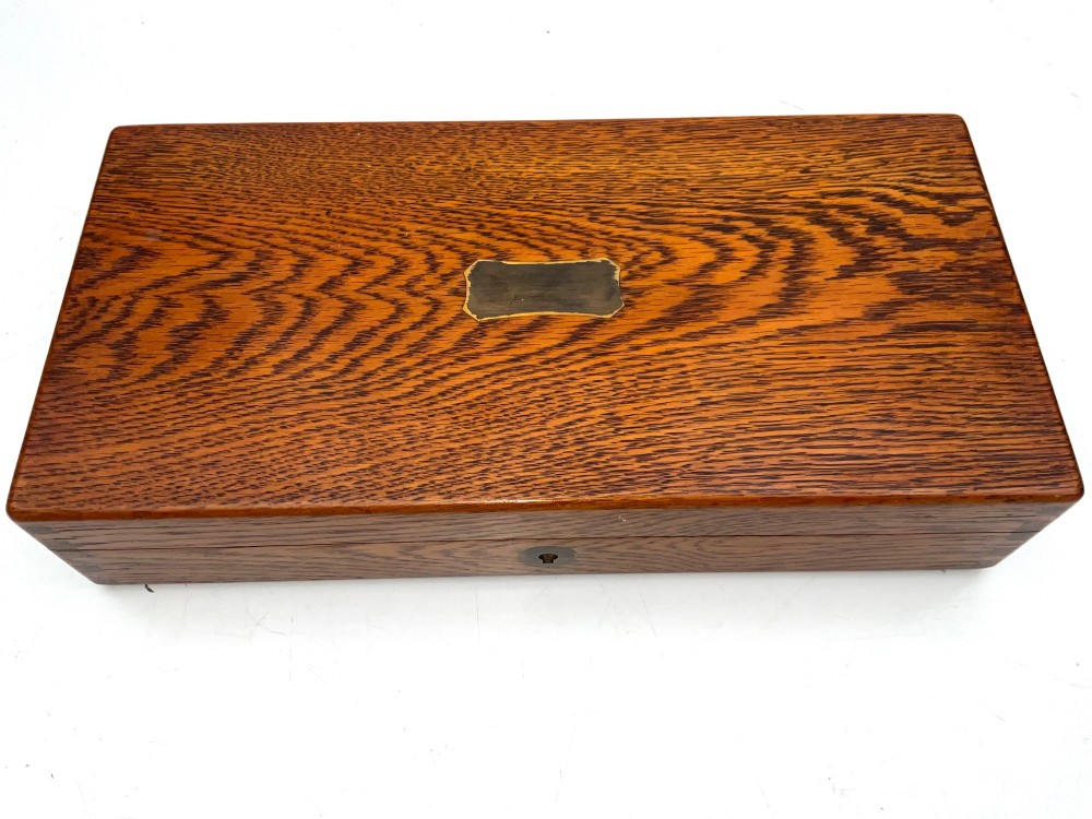 An open fitted wooden presentation case containing a .31 calibre percussion revolver, a brass powder flask, a bullet mould, and an instruction label attached to the inner lid. View XI