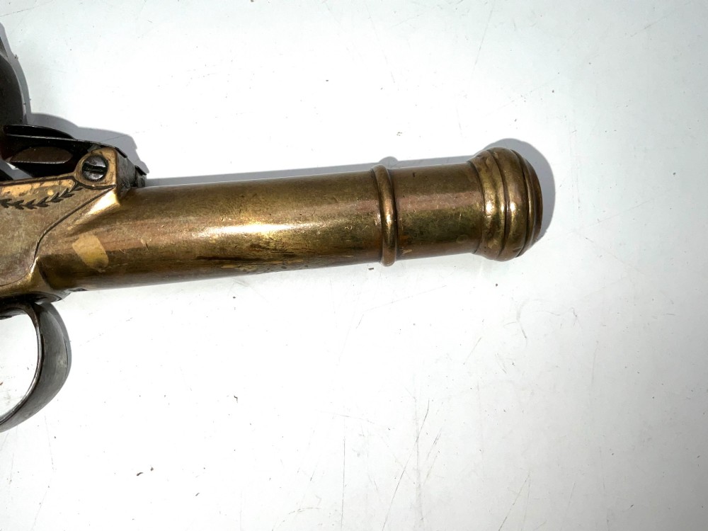 An antique Georgian flintlock overcoat pistol featuring a turned brass cannon barrel, engraved boxlock mechanism, and carved wooden handle. View IV