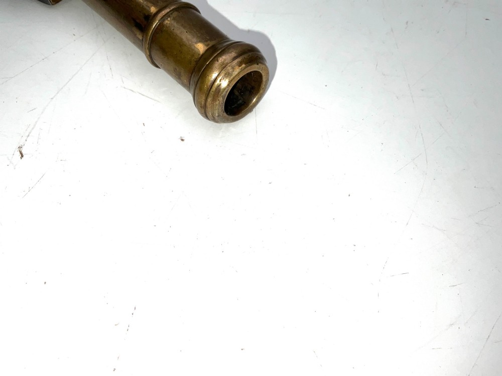 An antique Georgian flintlock overcoat pistol featuring a turned brass cannon barrel, engraved boxlock mechanism, and carved wooden handle. View X