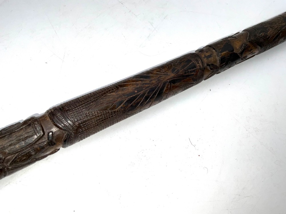 A tapered dark brown carved wooden Japanese bokken training stick featuring surface relief carvings. View IV