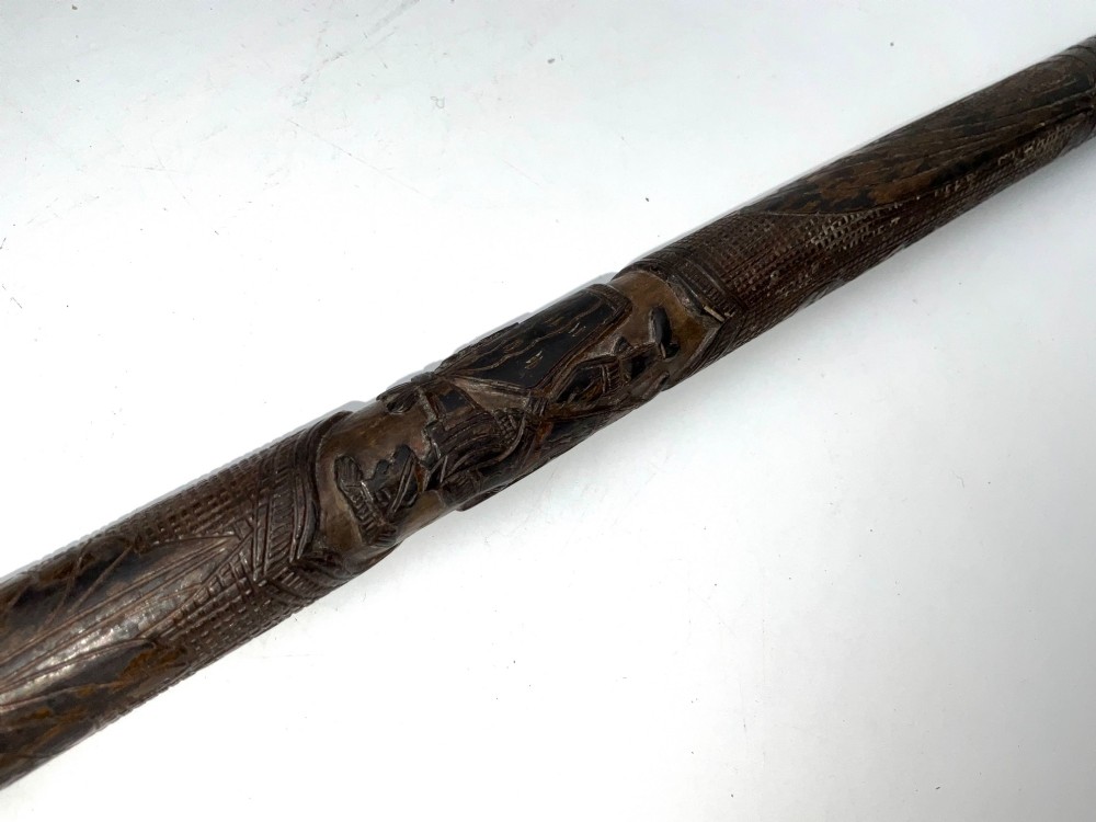 A tapered dark brown carved wooden Japanese bokken training stick featuring surface relief carvings. View V