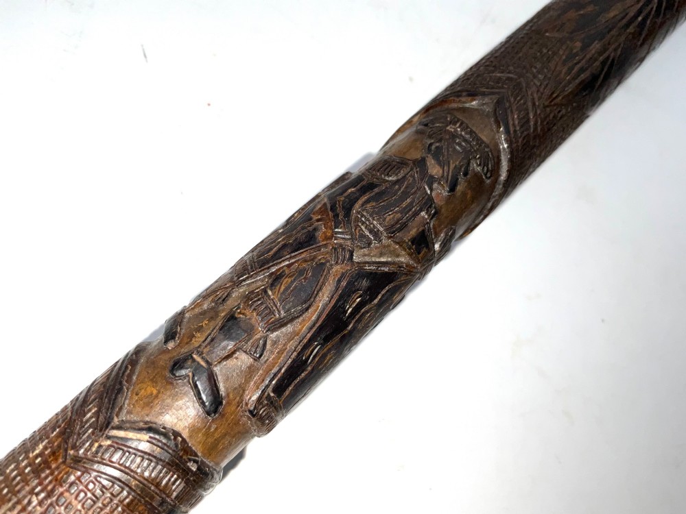 A tapered dark brown carved wooden Japanese bokken training stick featuring surface relief carvings. View VI