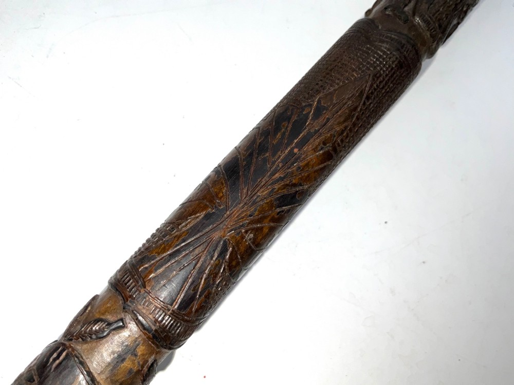 A tapered dark brown carved wooden Japanese bokken training stick featuring surface relief carvings. View VII