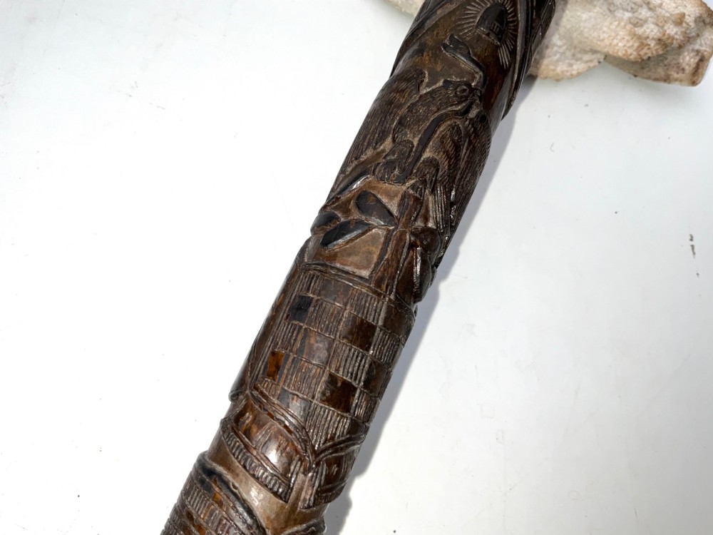 A tapered dark brown carved wooden Japanese bokken training stick featuring surface relief carvings. View VIII