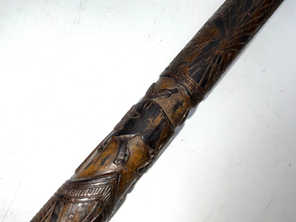 A tapered dark brown carved wooden Japanese bokken training stick featuring surface relief carvings. View IX